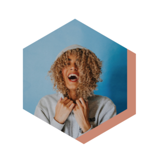 Photo of a woman with blond brown curly hear. she is smiling in a hoodie.